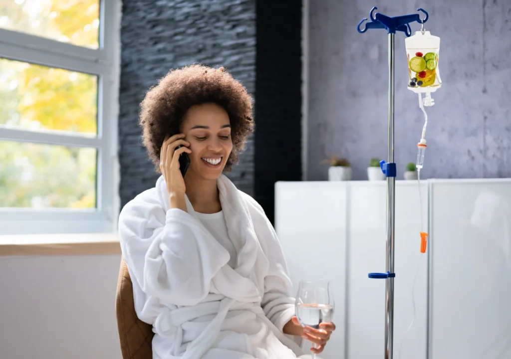 Black Woman receiving IV Therapy with a drink in her hand