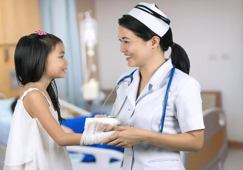 Nurse bandaging a young girl on her hand.